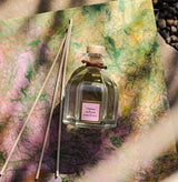 Collines de Provence Duftbouquet Kirschblüte 100 ml mit Glasflakon und Duftstäbchen auf einer kunstvoll gestalteten Unterlage im natürlichen Licht.