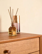 Collines de Provence Duftdiffuser Amber auf einer Holzkommode mit unscharfem Raumspray im Hintergrund