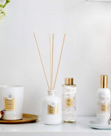 Collines de Provence Duftkollektion mit Duftkerze Baumwolle, Duftdiffuser Neroli, Duftdiffuser-Nachfüllung Neroli und Raumspray Baumwolle auf weißem Regal vor hellem Hintergrund.