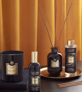 Collines de Provence Duftkollektion mit Duftkerze Schwarze Rose, Raumspray Ebenholz, Duftdiffuser Ebenholz und Duftdiffuser-Nachfüllung Ebenholz auf goldenem Tablett vor goldfarbenem Vorhang.