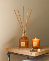 Collines de Provence Raumduft-Diffuser Mandarine & Yuzu mit Duftstäbchen und brennender Duftkerze auf Holztisch