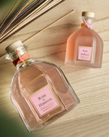 Collines de Provence Raumduft-Diffuser Rose & Hibiskus in zwei Glasflakons auf hellem Holzhintergrund