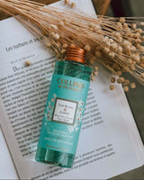 Collines de Provence Raumduft Nachfüllflasche Weißer Tee & Jasmin auf einem aufgeschlagenen Buch mit getrockneten Blüten als Stimmungsbild