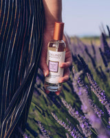 Collines de Provence Raumspray Lavendel 100 ml, in der Hand gehalten vor einem blühenden Lavendelfeld