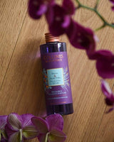 Collines de Provence Duftdiffuser-Nachfüllung Feige und Aloe Vera auf einer Holzoberfläche mit violetten Blüten im Vordergrund.
