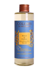 Collines de Provence Duftdiffuser-Nachfüllung Monoi und Passionsfrucht in transparenter Flasche mit hellgelber Flüssigkeit und blauem Etikett auf hellem Hintergrund.