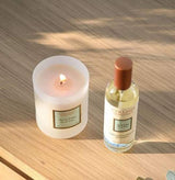 Collines de Provence Duftkerze Aloe Vera und Raumspray Aloe Vera auf einer Holzoberfläche im warmen Sonnenlicht mit brennender Kerze.