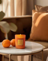 Collines de Provence Duftkerze Mandarine & Yuzu als stilvolle Dekoration auf einem Beistelltisch mit Mandarinen für eine frische und gemütliche Wohnatmosphäre.