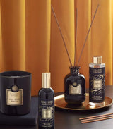Collines de Provence Duftkollektion mit Duftkerze Schwarze Rose, Raumspray Ebenholz, Duftdiffuser Ebenholz und Duftdiffuser-Nachfüllung Ebenholz auf goldenem Tablett vor goldfarbenem Vorhang.