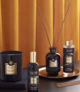 Collines de Provence Duftkollektion mit Duftkerze Schwarze Rose, Raumspray Ebenholz, Duftdiffuser Ebenholz und Duftdiffuser-Nachfüllung Ebenholz auf goldenem Tablett vor goldfarbenem Vorhang.