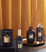 Collines de Provence Duftkollektion mit Duftkerze Schwarze Rose, Raumspray Ebenholz, Duftdiffuser Ebenholz und Duftdiffuser-Nachfüllung Ebenholz auf goldenem Tablett vor goldfarbenem Vorhang.