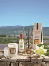 Collines de Provence Duftkerze, Raumspray und Duftdiffuser mit weißer Lilie auf einer Steinmauer vor einer Lavendellandschaft