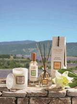Collines de Provence Duftkerze, Raumspray und Duftdiffuser mit weißer Lilie auf einer Steinmauer vor einer Lavendellandschaft