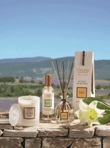 Collines de Provence Duftkerze, Raumspray und Duftdiffuser mit weißer Lilie auf einer Steinmauer vor einer Lavendellandschaft