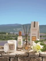 Collines de Provence Duftkerze, Raumspray und Duftdiffuser mit weißer Lilie auf einer Steinmauer vor einer Lavendellandschaft