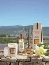 Collines de Provence Duftkerze, Raumspray und Duftdiffuser mit weißer Lilie auf einer Steinmauer vor einer Lavendellandschaft