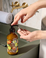 Handcreme Zitrusfrüchte von Collines auf grünem Waschbecken, eine Hand drückt den Pumpkopf und Creme tritt aus