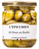 L'Épicurien milder Knoblauch mit Basilikum im Glas mit goldfarbenem Schraubdeckel und geschälten Knoblauchzehen in Kräutermarinade.