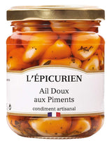 L'Épicurien milder Knoblauch mit Chili im Glas mit goldfarbenem Schraubdeckel und geschälten Knoblauchzehen in rötlicher Marinade.