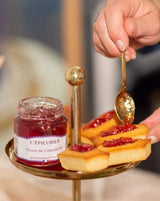 Serviervorschlag mit L'Épicurien Mohnblüten-Gelee auf kleinen Küchlein, daneben ein geöffnetes Glas und ein goldfarbener Löffel.