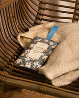 Panier des Sens Duftbeutel Baumwolle Coton Poudré auf Strickdecke im Korbstuhl, pudriger Baumwollblüten Duft.